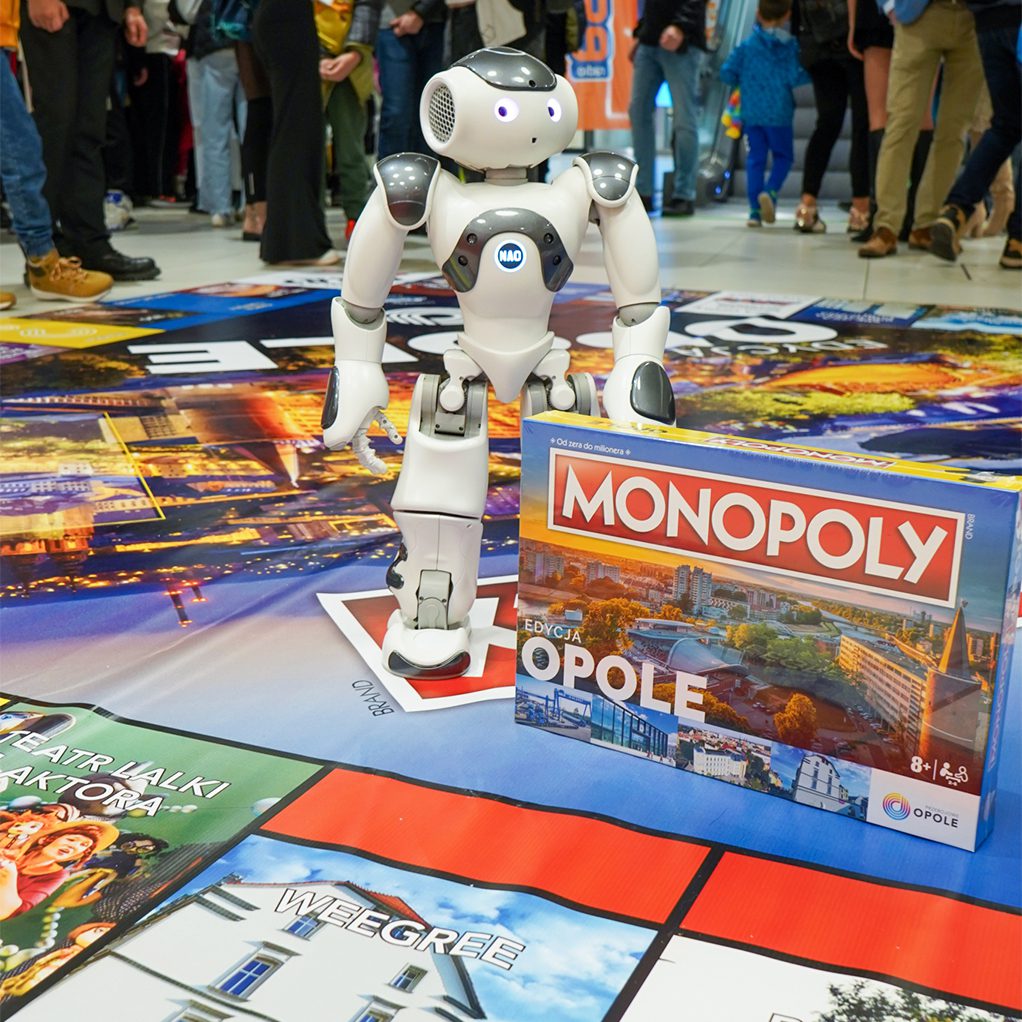 Robot Humanoidalny Nao stoi na planszy do gry Monopoly w trakcie eventu w Opolu.